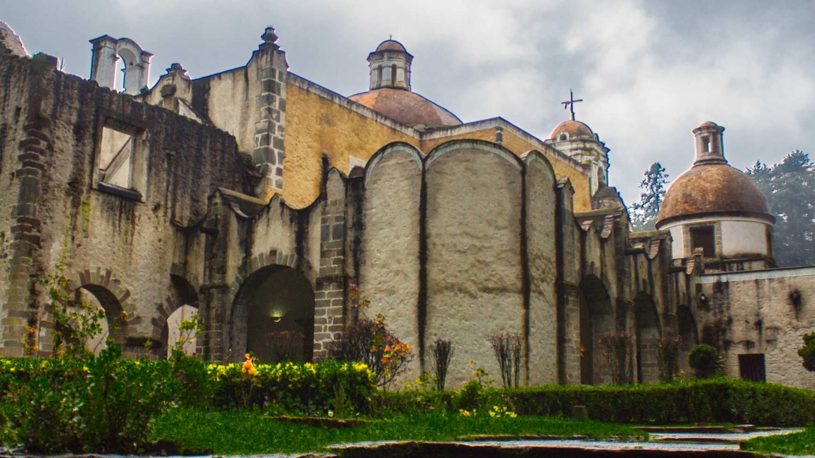 Claustro de arcos de piedra del histórico Ex-Convento del Desierto de los Leones inmerso en el bosque húmedo.