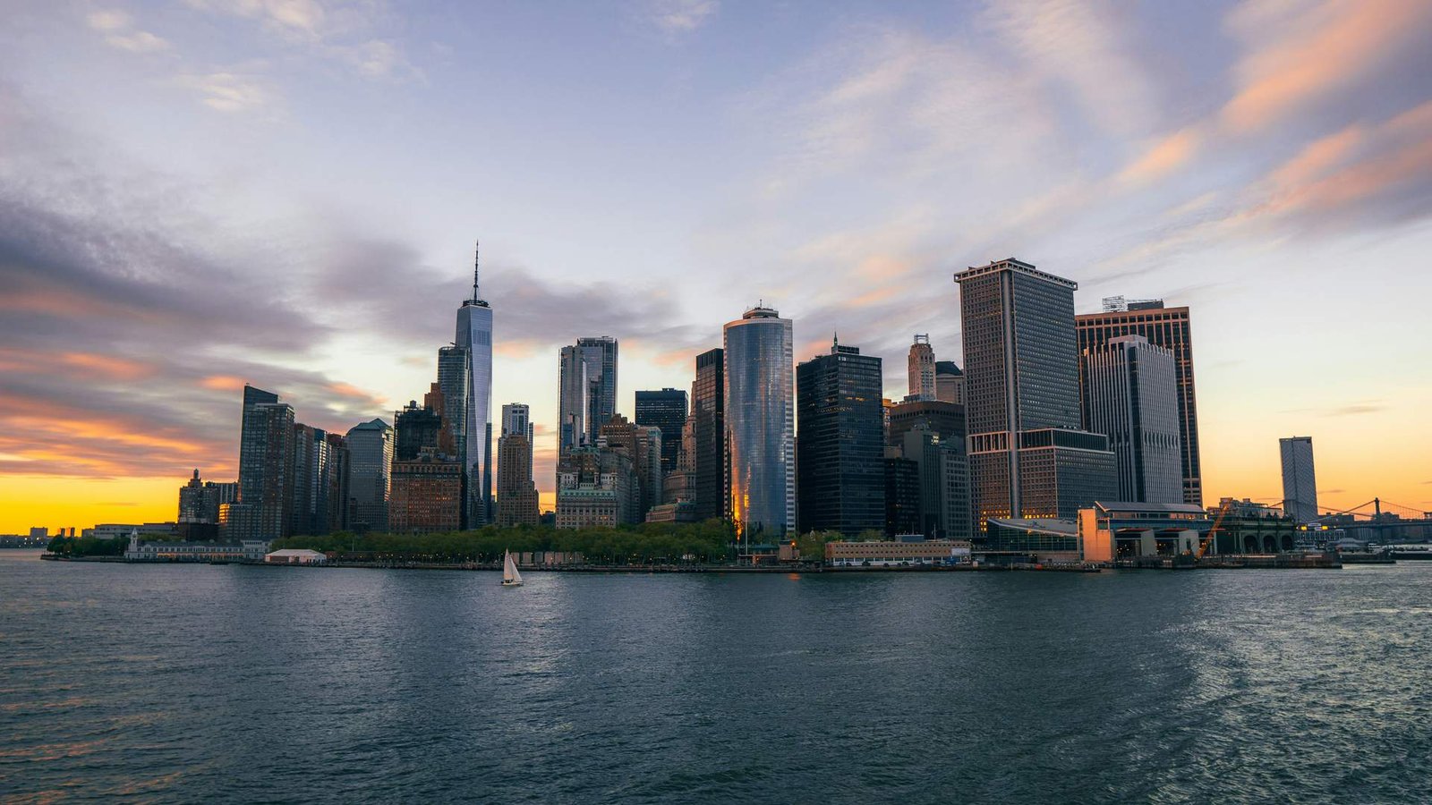 El emblemático ferry naranja de Staten Island navegando gloriosamente por el puerto de Nueva York bajo un espectacular cielo encendido al atardecer.